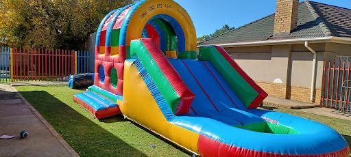 Colorful rainbow slide jumping castle with multi-colored bouncing area - available for hire in Cape Town